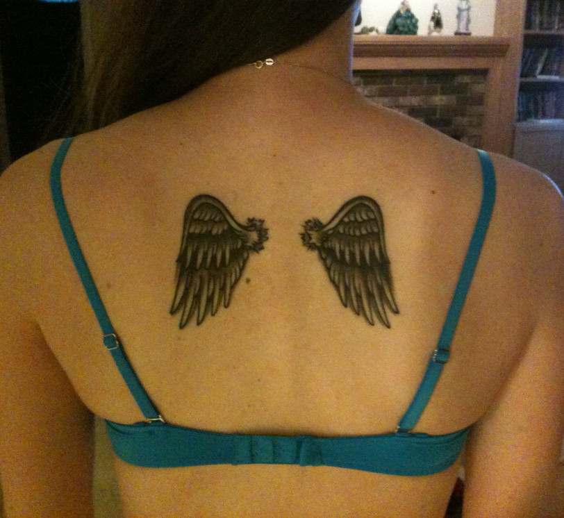 Photo of Christy's back with tattoo of small feather wings