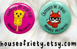 Two badge pins, with cartoon otter and fox, indicating individual has been vaccinated